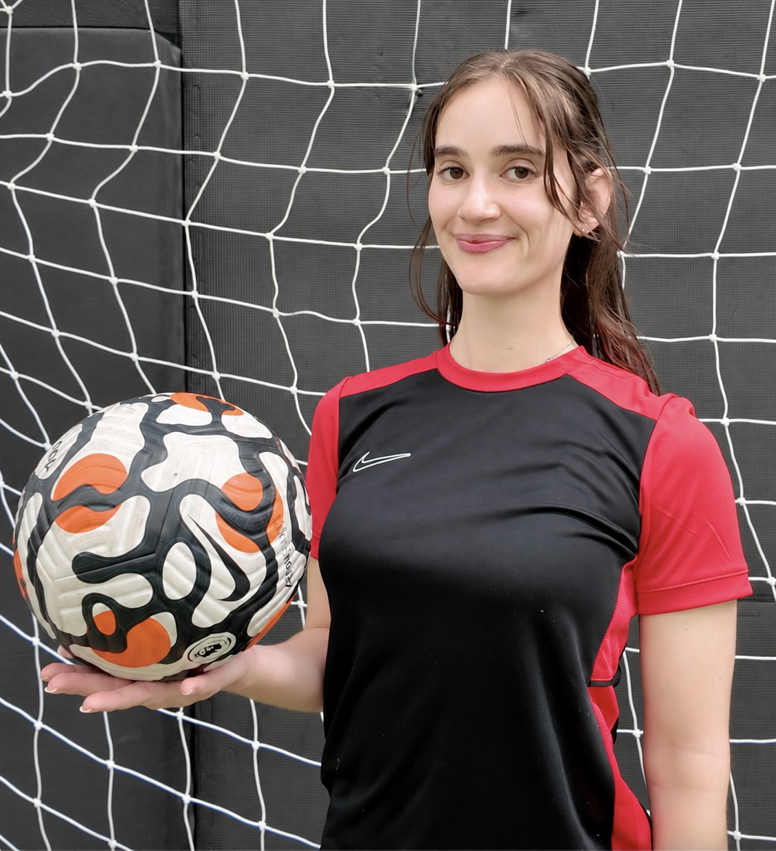 Kynthia, founder of Own Your Ground, holding a soccer ball.